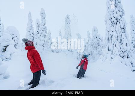 Femme gaie avec son fils s'amusant à jouer avec la neige, Laponie, Finlande Banque D'Images