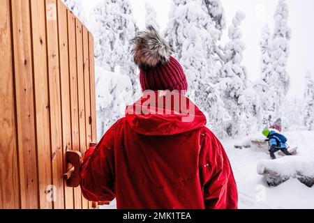 Vue arrière d'une femme regardant ses enfants heureux jouant dans la neige, ISO Syote, Ostrobothnia du Nord, Laponie, Finlande Banque D'Images
