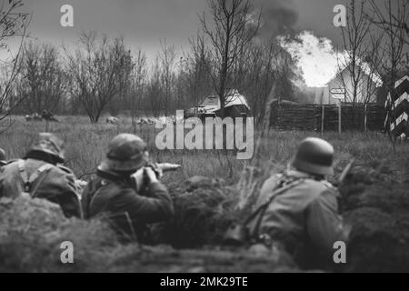 Les réacteurs ont armé des fusils et se sont habillés comme soldats allemands de l'infanterie Wehrmacht de la Seconde Guerre mondiale combattant de manière défésive dans le Trench. Lutte contre le véhicule de combat Banque D'Images