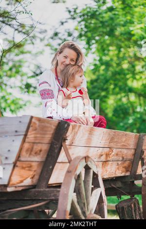 Belle paysanne en vêtements brodés avec fille sur un chariot Banque D'Images