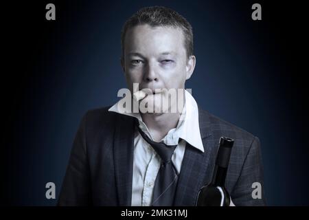 Homme d'affaires en costume boire de l'alcool dans une bouteille. Ton Banque D'Images