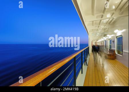 Vue sur les passagers marchant sur le pont de promenade d'un bateau de croisière la nuit. Banque D'Images