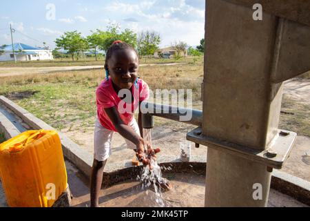 Promotion de la bonne hygiène : les jeunes filles africaines se lavent les mains à une pompe à eau manuelle Banque D'Images