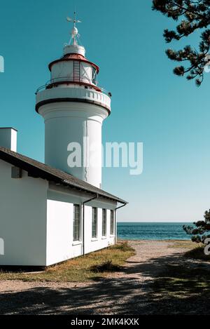 Danemark, Jutland, Djursland: Le phare rond blanc Sletterhage sur la péninsule d'Helganaes au soleil contre un ciel bleu et sans nuages. Banque D'Images