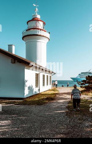 Les gens regardent un bateau de croisière passant le phare de Sletterhage FYR sur la péninsule de Helgenæs à Djursland au soleil, Jutland, Danemark Banque D'Images