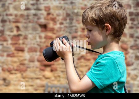 Un garçon de cinq ans apprend à utiliser un appareil photo Banque D'Images