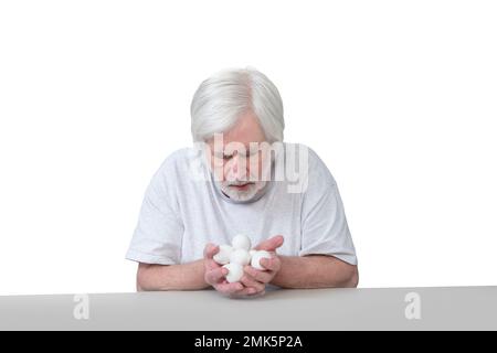 Plan horizontal d'un homme âgé assis à une table tenant ses précieux œufs de poulet blanc chers. Isolé sur blanc. Beaucoup d'espace de copie. Banque D'Images