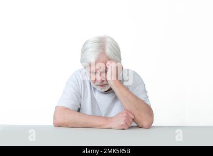 Plan horizontal d'un vieil homme fatigué dormant à une table en appuyant sa tête sur sa main. Isolé sur blanc. Beaucoup d'espace de copie. Banque D'Images