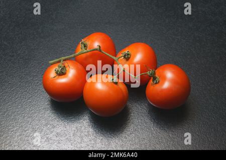 branche de tomates sur une table sombre Banque D'Images