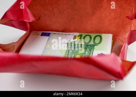 Argent cadeau emballé dans du papier rouge. Cadeau et bonus vacances financières Banque D'Images