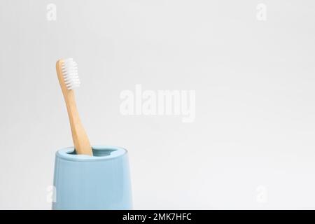 Brosse à dents en bambou dans un support isolé sur blanc Banque D'Images