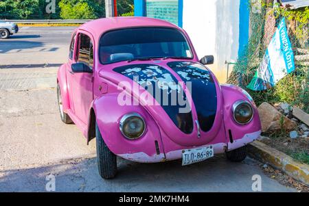 Diverses voitures roses colorées anciennes cassées rouillées et endommagées et des voitures anciennes classiques à Puerto Escondido zicatela Oaxaca Mexique. Banque D'Images