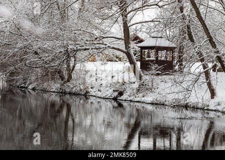 Un petit belvédère en bois dans les profondeurs d'une forêt d'hiver près d'un ruisseau de montagne froid et noyés marchent le long de lui, grimpant d'une vallée forestière. Banque D'Images