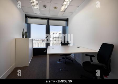 Petit bureau avec bureau en face avec chaises noires pivotantes dans un bureau avec fenêtres donnant sur la ville Banque D'Images