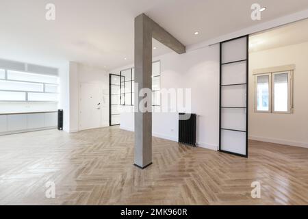 Maison vide avec un style loft moderne avec poutres et colonnes en béton brut, sols en grès métallique et grandes fenêtres en métal noir Banque D'Images