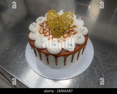 pâtissière de chef finissant des gâteaux dépoli au caramel salé avec des meringues et un surmatelas fait main au coeur doré chocolat Banque D'Images