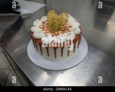 pâtissière de chef finissant des gâteaux dépoli au caramel salé avec des meringues et un surmatelas fait main au coeur doré chocolat Banque D'Images