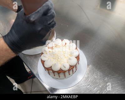 pâtisserie du chef préparant des gâteaux blancs dépolis au caramel salé avec des meringues sur le dessus Banque D'Images