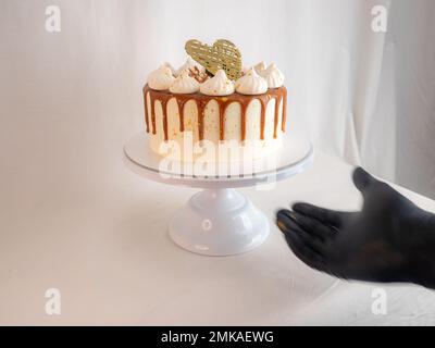 pâtissière de chef finissant des gâteaux dépoli au caramel salé avec des meringues et un surmatelas fait main au coeur doré chocolat Banque D'Images