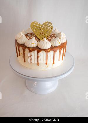 pâtissière de chef finissant des gâteaux dépoli au caramel salé avec des meringues et un surmatelas fait main au coeur doré chocolat Banque D'Images