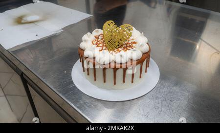 pâtissière de chef finissant des gâteaux dépoli au caramel salé avec des meringues et un surmatelas fait main au coeur doré chocolat Banque D'Images