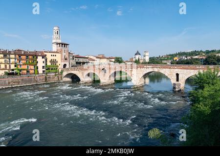 L'eau se déplaçant rapidement sous les arches du pont Ponte Pietra qui traverse l'Adige de Fiume à Vérone, en Italie, s'envole dans un ciel bleu clair Banque D'Images