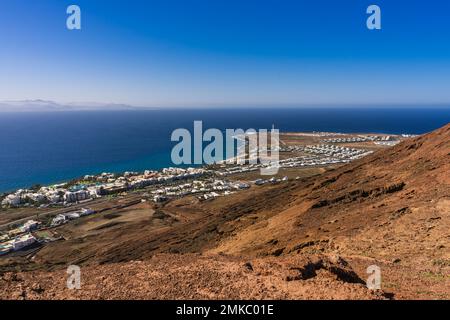 En regardant vers le quartier autour du phare de Pechiguera qui se trouve à une extrémité de Playa Blanca à Lanzarote. De l'autre côté de la mer, les volcans de Fue Banque D'Images