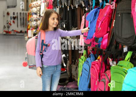 Petite fille d'école choisissant sac à dos dans le supermarché Banque D'Images