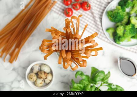 Nouilles de sarrasin non cuites et ingrédients frais sur une table en marbre blanc, à plat Banque D'Images