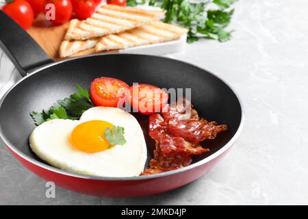 Petit déjeuner savoureux avec œufs frits en forme de cœur sur table grise Banque D'Images