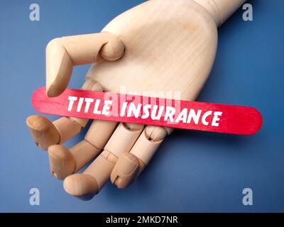Main en bois tenant bâton de glace avec mot TITRE ASSURANCE. Banque D'Images
