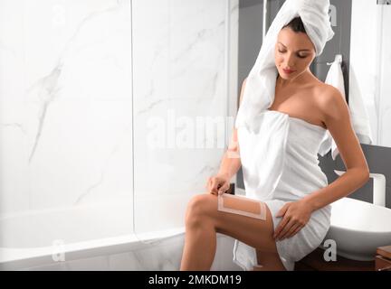 Une jeune femme se cirant les jambes dans la salle de bains. Procédure d'épilation Banque D'Images