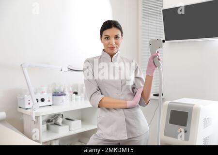 Jeune femme tenant un épilateur laser professionnel dans un salon de beauté Banque D'Images