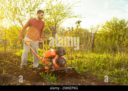 Un fermier travaille dans le champ, labourant la terre avec une charrue sur la ferme. Un charpiller sur une promenade derrière un cultivateur à moteur. Saison de labour. Culte organique Banque D'Images