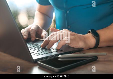 Vue en gros plan partielle de l'homme d'affaires qui tape sur un ordinateur portable sur son lieu de travail. Gros plan homme d'affaires mains travail ordinateur portable de recherche ou de saisie de texte messag Banque D'Images