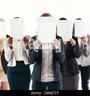 Les femmes derrière l'entreprise. un groupe d'hommes d'affaires méconnus portant des morceaux de papier vierges sur leur visage sur un fond blanc. Banque D'Images