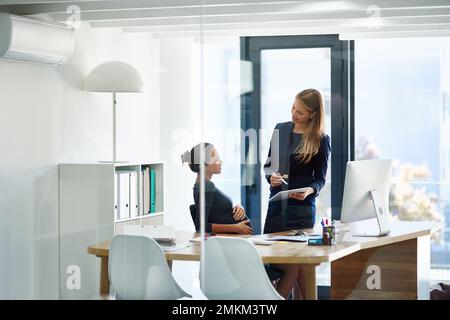 Vous manquerez tous pendant votre séjour. une femme d'affaires enceinte et un collègue utilisant une tablette numérique ensemble dans un bureau. Banque D'Images