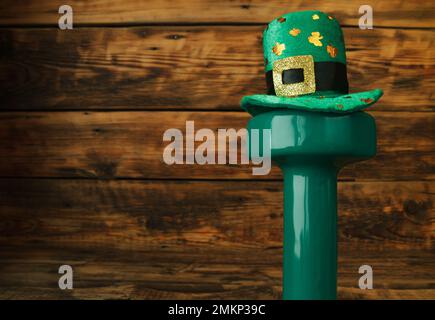 Green Gym haltères portant un chapeau de trèfle à feuilles de shamrock irlandais pour St. Patrick. Composition de pose plate d'entraînement de fitness avec espace de copie sur bois. Banque D'Images