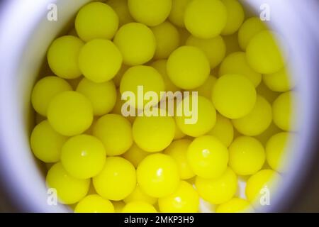 Vitamines jaune vif de l'acide ascorbique dans un pot blanc d'un regard de goulot de bouteille Banque D'Images