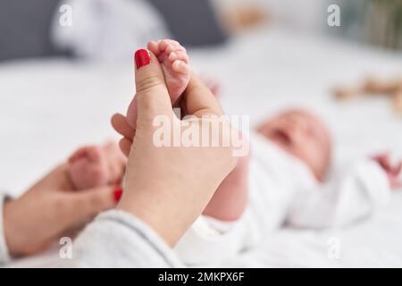 Adorable bébé caucasien couché sur le lit ayant des pieds massants à la chambre Banque D'Images