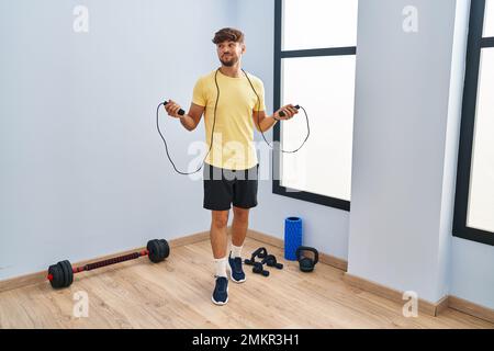 Homme arabe avec formation de barbe avec corde de saut souriant regardant sur le côté et regardant loin de penser. Banque D'Images