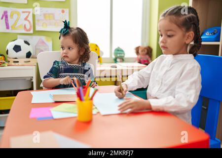 Frère et soeur élèves assis sur table de dessin sur papier à la maternelle Banque D'Images