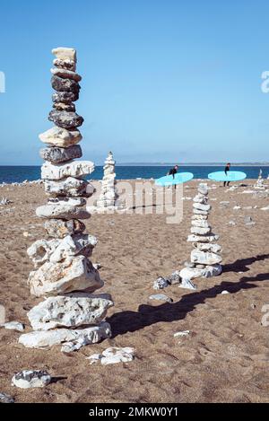 Deux surfeurs se promènent devant la pierre de la ville de cairns, sur la plage de sable de Klitmöller, sur la côte ouest de Jutland, au Danemark Banque D'Images