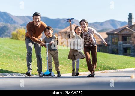 Un jeune couple avec des enfants à jouer dans le scooter Banque D'Images