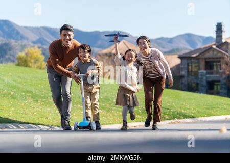 Un jeune couple avec des enfants à jouer dans le scooter Banque D'Images