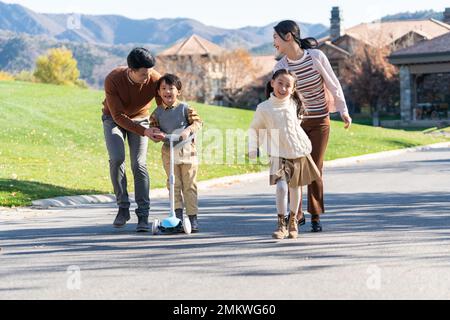 Un jeune couple avec des enfants à jouer dans le scooter Banque D'Images