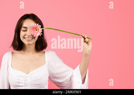 Bonne jeune femme caucasienne mettant la fleur à l'œil, profiter de temps libre, le style de vie, a le plaisir Banque D'Images
