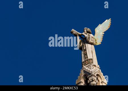 Trompette de soufflage chérubin Angel. Une statue médiévale datant de 13th ans au sommet de l'église Saint-Michel de Lucques (avec ciel bleu et espace copie) Banque D'Images