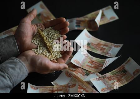 Le concept du coût du grain. 5000 roubles de billets autour d'une poignée de grain de terre. La faim dans le monde. Banque D'Images