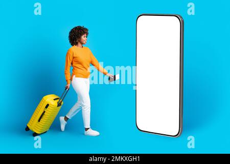 Jeune femme noire excitée qui se dirige vers un téléphone portable, mockup Banque D'Images